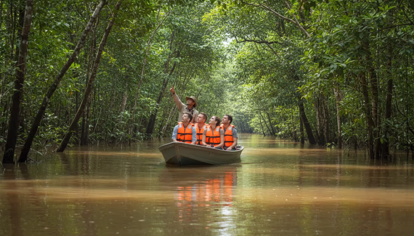 Small skiff boat with tourists and a naturalist guide navigating a narrow flooded forest channel in the Amazon rainforest