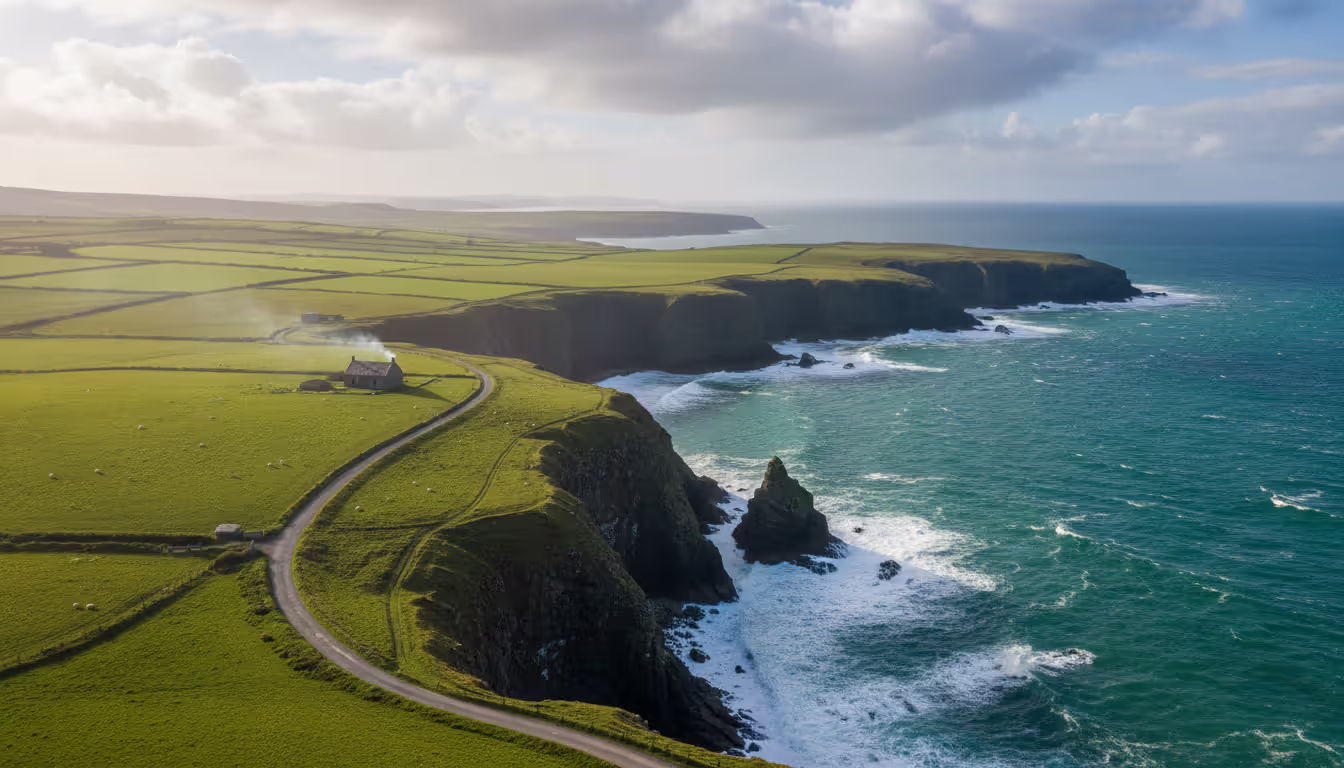 Dramatic Wild Atlantic Way coastal cliffs with green fields narrow road and a lone stone cottage under a cloudy sky with sunbeams