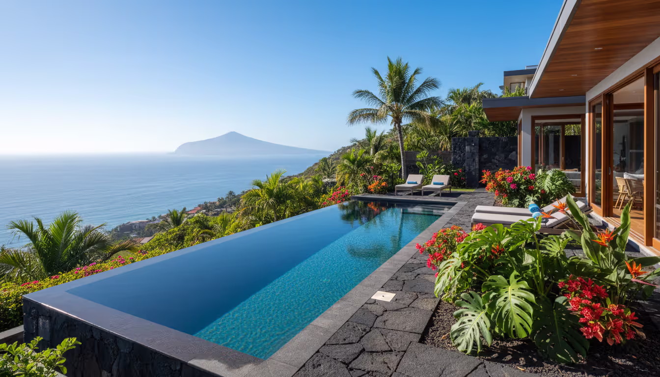 Hillside infinity pool villa overlooking the Atlantic Ocean surrounded by volcanic rock and lush tropical vegetation on a sunny day
